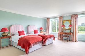 A bedroom with two beds, a desk, and a chair.