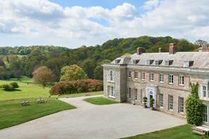 A large stone building with a formal garden and a gravel driveway.