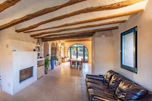Un intérieur chaleureux avec des poutres apparentes, une cheminée, un coin repas et un canapé en cuir.