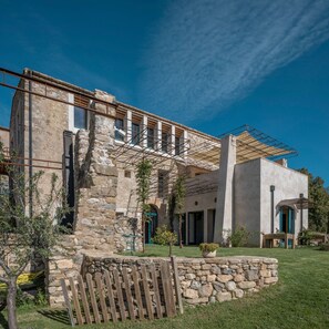 Ein Gebäude aus Stein mit einem modernen Anbau, einem Holzzaun und einem strahlend blauen Himmel.