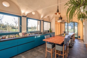 Eine moderne Küche mit einer großen Kochinsel, blauen Schränken und einem Holztisch.