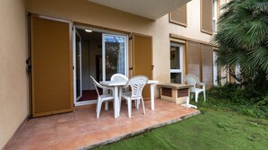 Eine Terrasse mit Tisch und Stühlen, eine Schiebetür und ein kleiner Gartenbereich.
