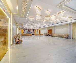 A spacious hall with rows of chairs and tables, ornate chandeliers, and decorative wall panels. - Suite Room Amar Resorrt (Motihari)