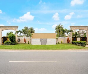 A gated entrance with a central staircase leading to a building, surrounded by palm trees and a clear sky. - Suite Room Amar Resorrt (Motihari)