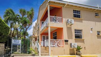 A multi-story building with balconies, air conditioning units, and a gated entrance.