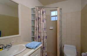 A bathroom with a shower curtain, a sink, and a toilet. - Best E Villas Providence (Providence)