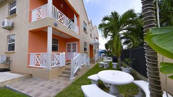 A two-story building with balconies, outdoor seating, and palm trees.