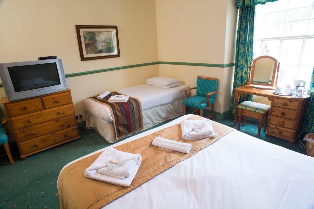A hotel room with a bed, a television, a desk with a mirror, and a chair.