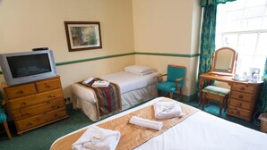 Ein Hotelzimmer mit einem Bett, einem Fernseher, einem Schreibtisch mit Spiegel und einem Sessel.
