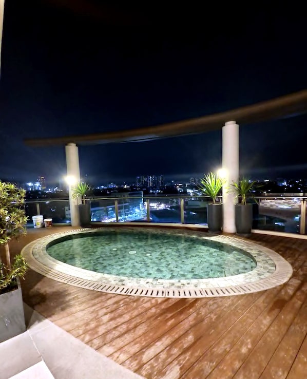 A rooftop pool area with a view of the city at night.