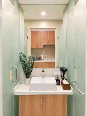 Un baño con un lavamanos blanco, armarios de madera, un espejo y una planta en maceta.