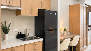 Een moderne keuken met houten kastjes, een zwarte koelkast, een spoelbak en een eethoek met stoelen.