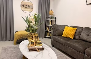 Una sala de estar con un sofá, una mesa de centro con objetos decorativos, una estantería y un cartel que dice 'HOME'.