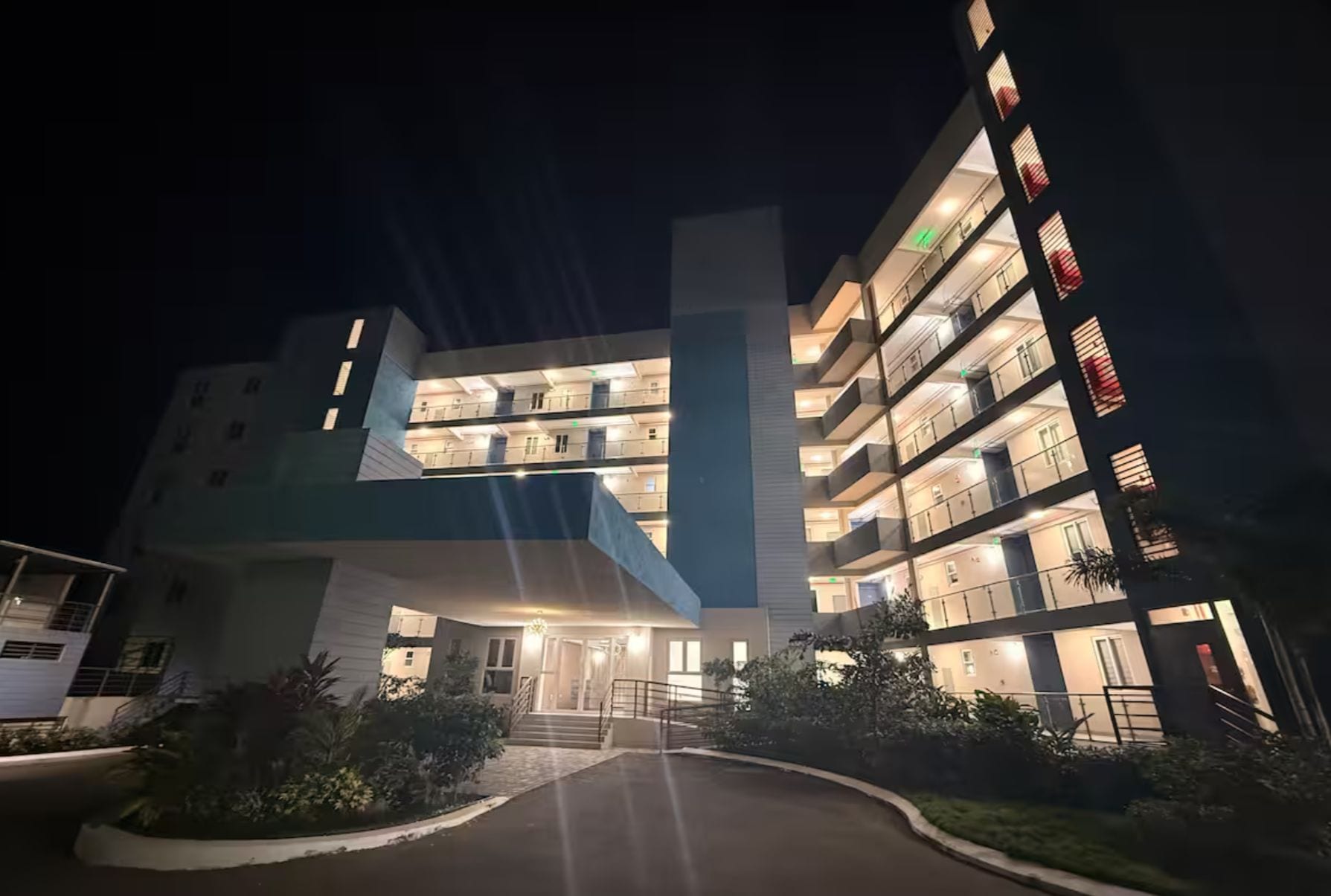 Un hotel de varios pisos con una entrada central y balcones en cada planta.