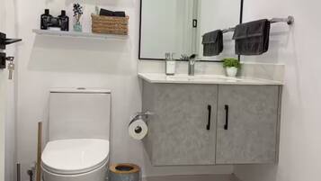 Un baño moderno con inodoro, lavamanos y un mueble.