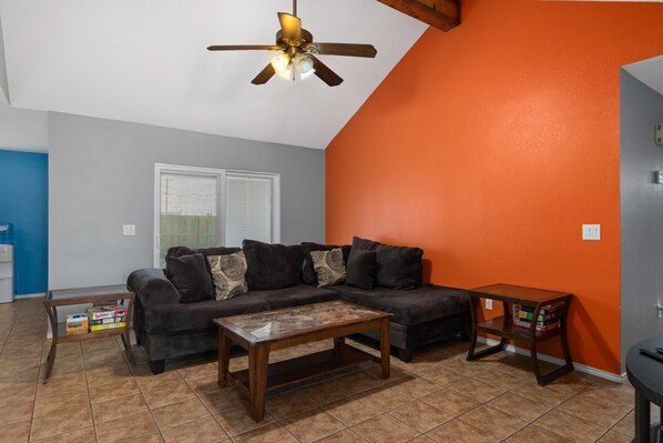 A living room with a dark-colored sofa, a wooden coffee table, and a ceiling fan. - Cute 2 bedroom home in port Isabel with backyard (Port Isabel)