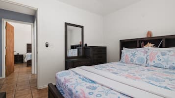 Een slaapkamer met een bed, een kaptafel, een spiegel en een nachtkastje.