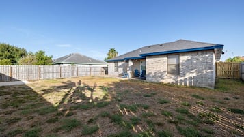 Een woonhuis met een losstaande garage, een overdekt terras en een omheinde achtertuin.