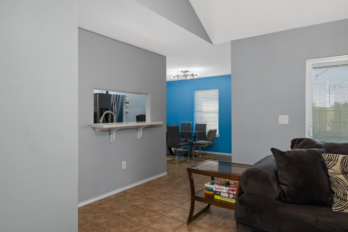 Een woonkamer met een donkerbruine bank, een bijzettafeltje met boeken, een klein plankje met een spiegel en een blauwe muur.