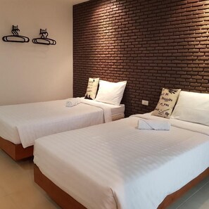 Habitación de hotel con dos camas individuales, una pared de ladrillo decorativa y almohadones decorativos.
