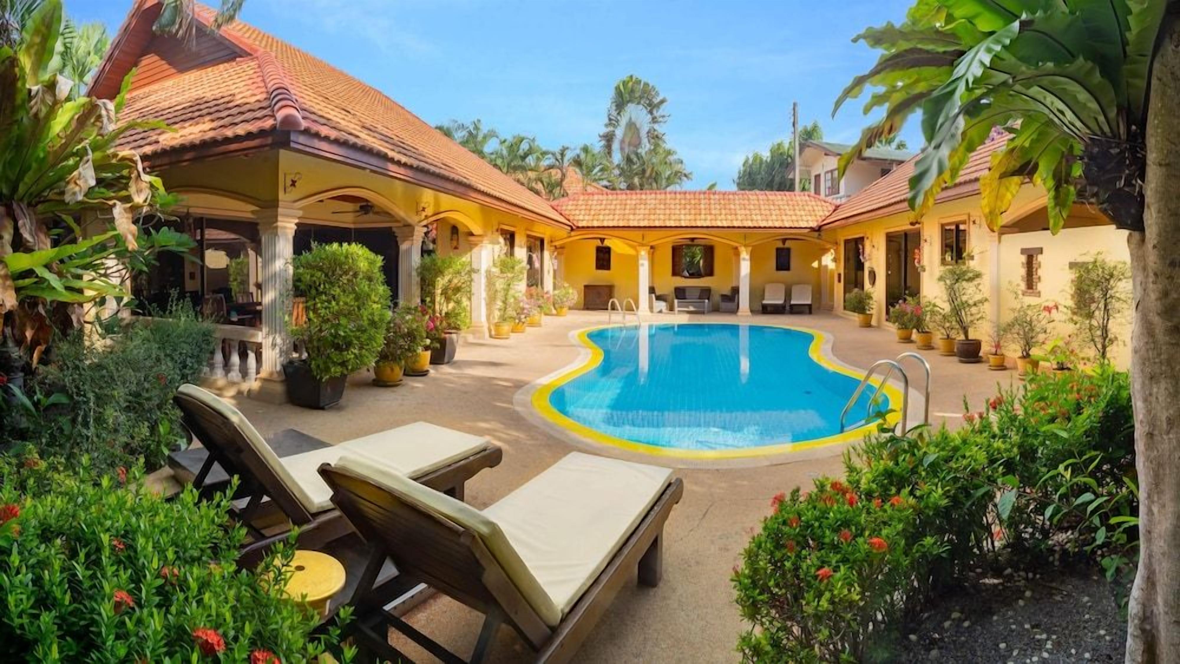 A pool area with lounge chairs, a covered seating area, and potted plants.