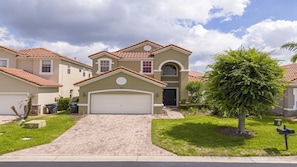 A residential house with a garage, a driveway, and a well-maintained lawn. - 5BR Tuscan Hills Villa Pool & Themed Rooms (Davenport)