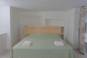 A single bed with a wooden headboard in a room with white walls and a green bedspread. - La Corte Romana · Il fascino nel centro di Verona (verona)