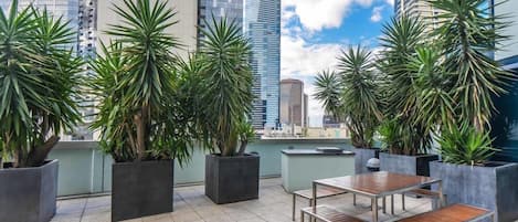 A rooftop terrace with potted plants and outdoor seating.