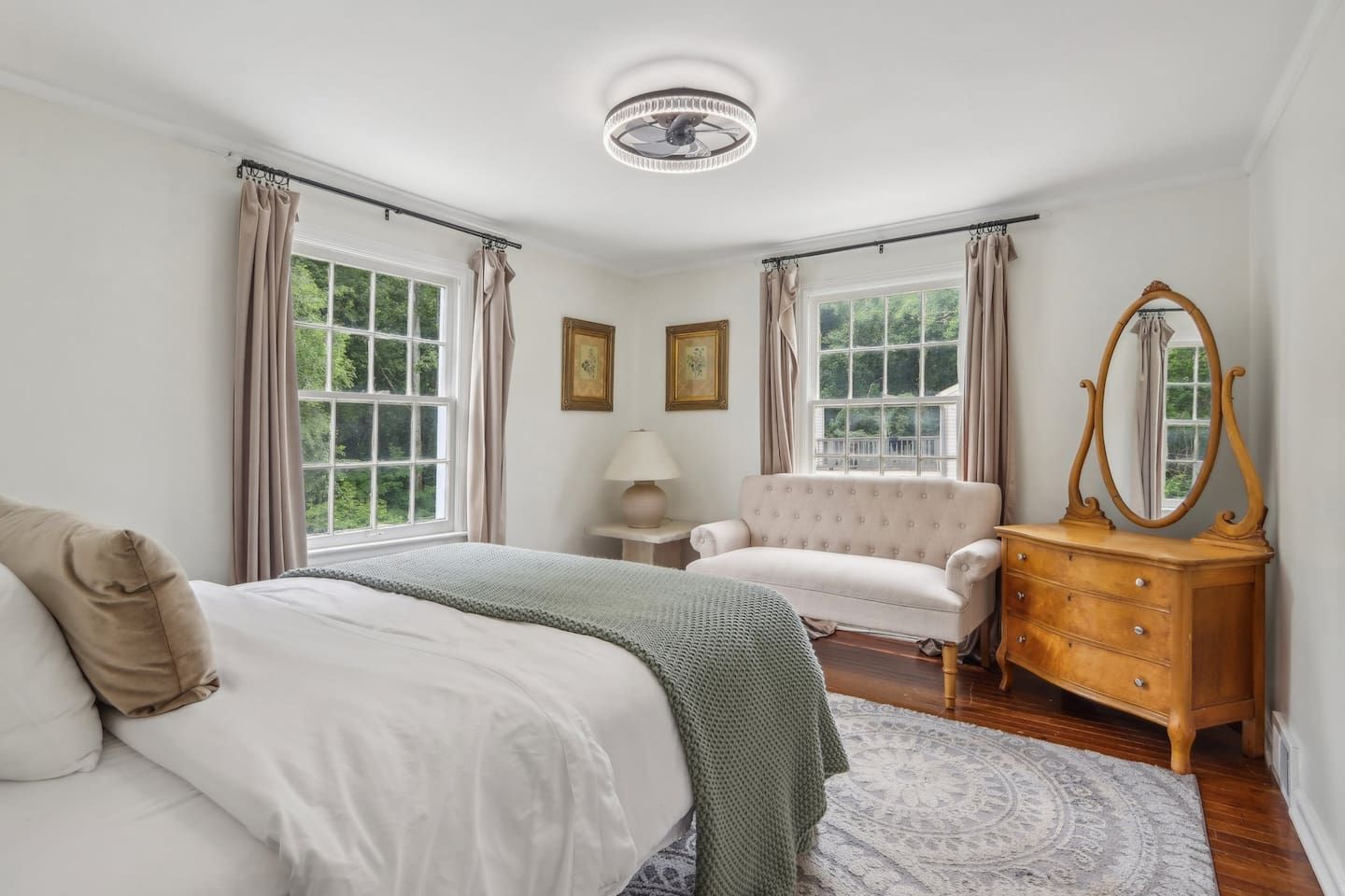 Une chambre à coucher avec un lit, une commode, une chaise et une fenêtre avec des rideaux.