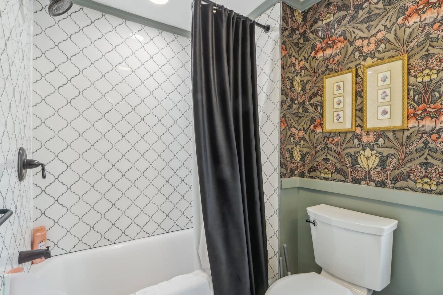 A bathroom with a shower, toilet, and a wall with floral wallpaper.