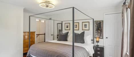 A four-poster bed with a headboard, a bedside table with a lamp, and a patterned rug.