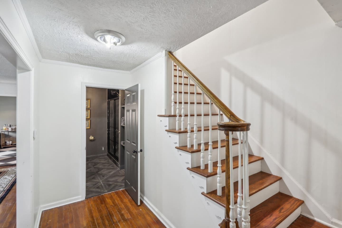 A staircase with wooden steps and white balusters, leading to a landing with a door.