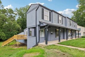 A two-story building with a covered porch and a wooden staircase leading to a deck. - Modern Broad Ripple Home | 4BR/3 BA | Walkable (Indianapolis)