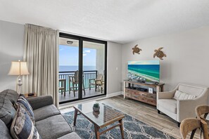 A living room with a view of the ocean, a sofa, a coffee table, and a TV on a wooden stand. - 🌊 Enjoy Stunning Gulf Views | Fabulous Amenities | SunDestin 1803🌊 (Destin)