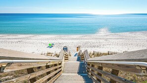 Eine Holztreppe führt zu einem Strand mit freiem Blick auf das Meer.
