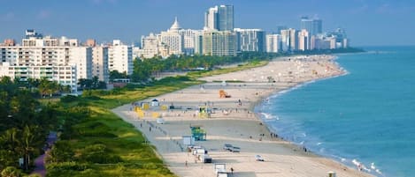 A coastal cityscape with a wide beach, high-rise buildings, and a clear sky.