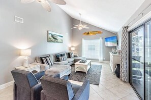 Un salon moderne avec un canapé, une table basse et un téléviseur.