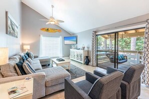 Ein modernes Wohnzimmer mit einer Sofagarnitur, einem Couchtisch und einem Fernseher.