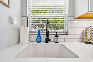 A modern kitchen with a white sink, a blue Dawn Powerwash bottle, and a hand soap dispenser. - Luxury Lakefront Cottage - Private Hot Tub -Stunning Sunset Views near UCF (Orlando)