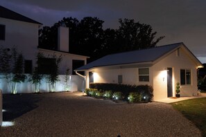 Una casa moderna de dos pisos con entrada de grava y luces exteriores iluminadas.