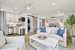 A modern living room with a sofa, coffee table, and a dining area. - Luxury Lakefront Cottage - Private Hot Tub -Stunning Sunset Views near UCF (Orlando)