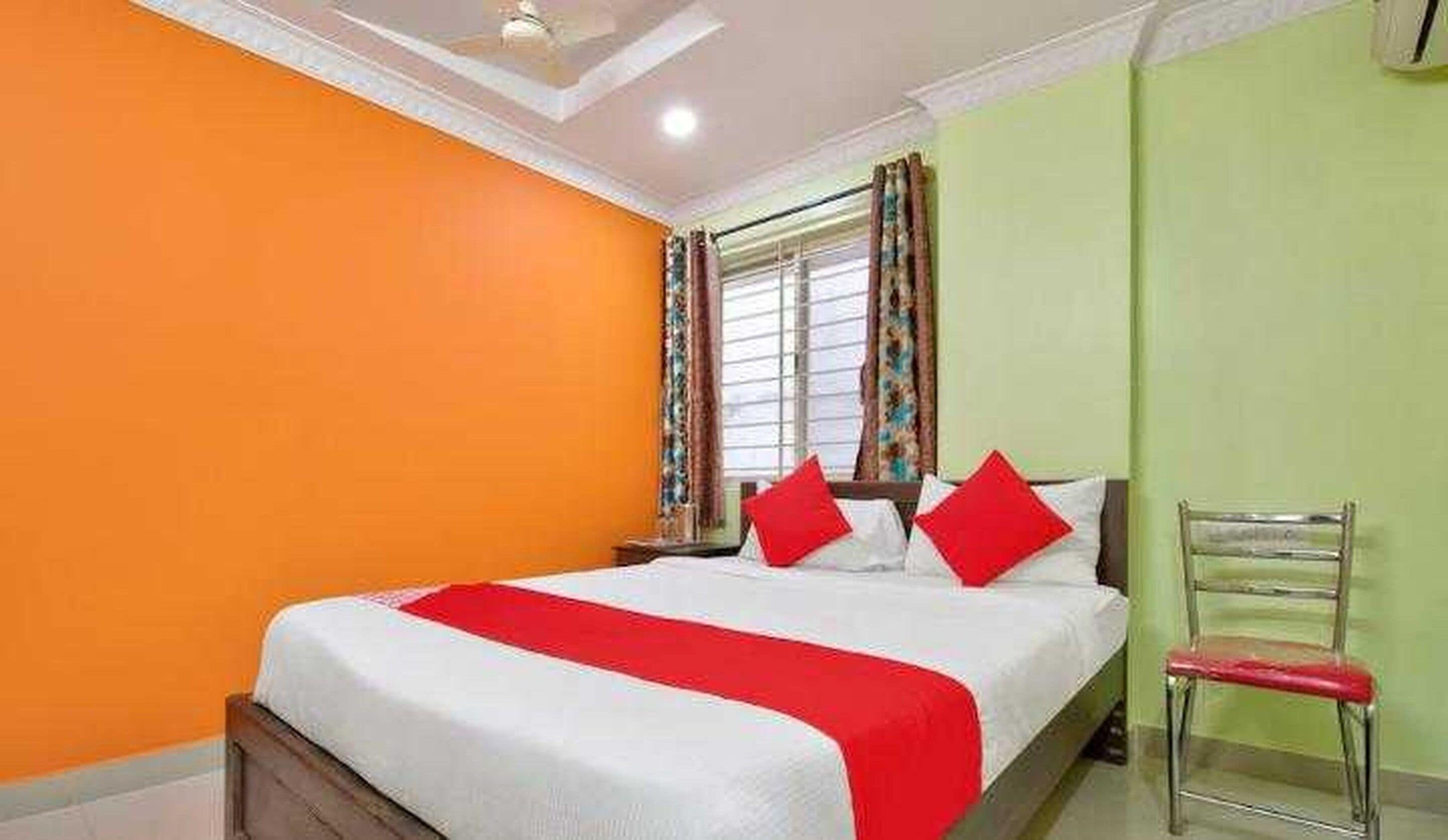 A bedroom with a bed, a chair, and a window with curtains.