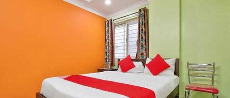A bedroom with a bed, a chair, and a window with curtains.