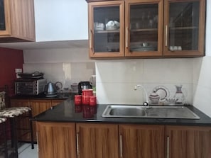 A kitchen with wooden cabinets, a black countertop, a sink, and various kitchen appliances. - Adorable 2-bedroom house in soothing Avissawella neighborhood (Avissawella)