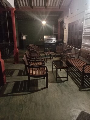 An outdoor seating area with wooden furniture and a barbecue grill.