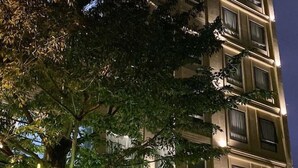Ein mehrstöckiges Hotel mit einem gut sichtbaren Eingang, einer Treppe, die zum Empfangsbereich führt, und einer Beschilderung, die es als Hotel und Apartmentkomplex kennzeichnet.