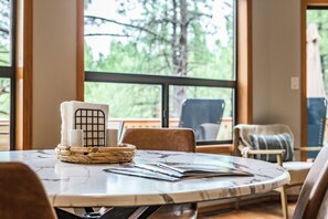 A round table with a marble top, a woven basket, and a stack of magazines. - Stylish Zen Mountain Villa: Hot Tub, Games & Views (Flagstaff)