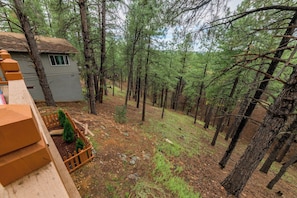 A residential area with a house, a wooden fence, and a forested hillside. - Stylish Zen Mountain Villa: Hot Tub, Games & Views (Flagstaff)