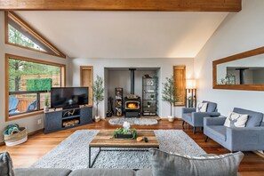 Een moderne woonkamer met een televisie, open haard en zithoek.