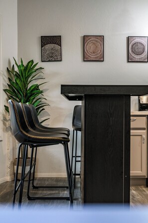Een bar met twee stoelen, een bar en drie ingelijste kunstwerken aan de muur.